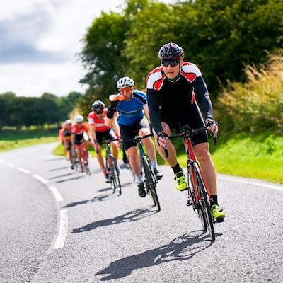 Gruppe von Rennradfahrern beim Training auf der Straße, symbolisch für sportmedizinische Labordiagnostik zur Analyse von Leistungsfähigkeit, Stoffwechsel, Hormonstatus und Herz-Kreislauf-Gesundheit.